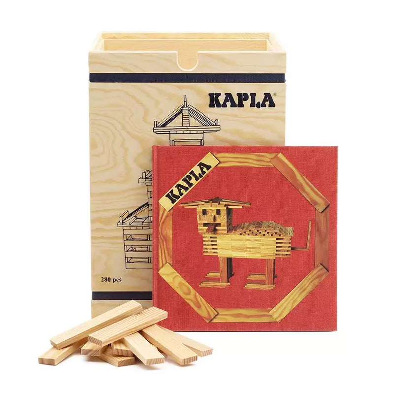 The KAPLA® Construction 280 Planks in Wooden Box is showcased alongside an open book with a red cover, featuring a wooden animal built from KAPLA planks. This set promotes creativity stimulation, and several loose wooden planks are scattered in front of the elegant storage box.