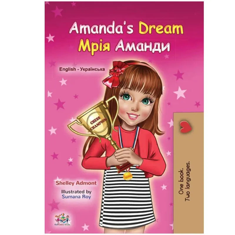 The cover of "Dual Language Book Amanda's Dream English/Ukrainian Children's Book" shows a smiling girl with brown hair, red bow, striped skirt, and trophy against a pink starry background. Title is in both English and Ukrainian.