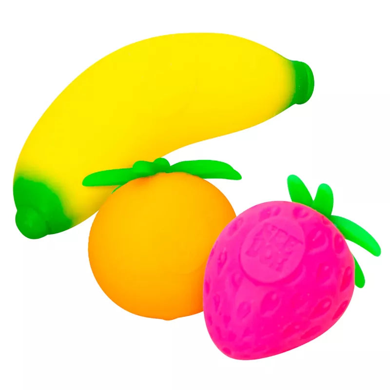 Three colorful plastic fruit toys isolated on a white background: a yellow banana, an orange orange, and a pink Groovy Fruits Needoh stress ball, each with green leaf details.