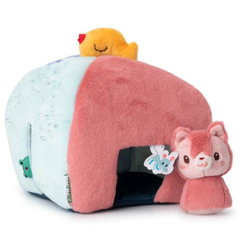 The Lilliputiens I'm Discovering Jules' House and 4 Hidden Rattles is a plush animal house in light blue and pink with a small red and yellow chick on top. It features an open entrance, perfect for peek-a-boo, with a nearby pink and white stuffed cat as part of this delightful baby toy.