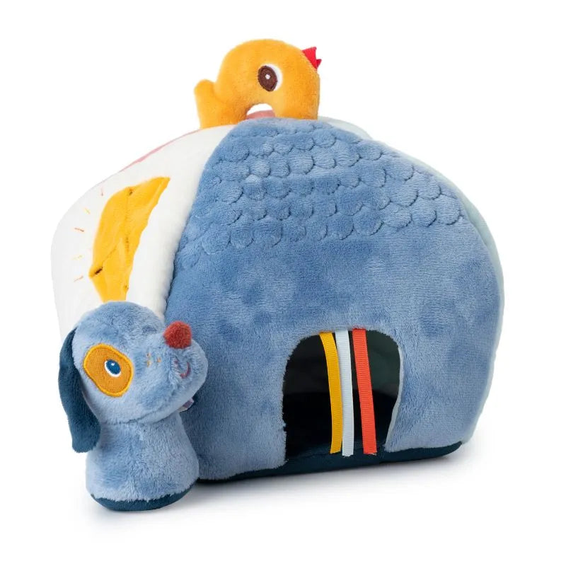 The Lilliputiens I'm Discovering Jules' House and 4 Hidden Rattles is a baby toy shaped like a blue house with a dog's head and a small yellow chick on top. It features colorful ribbons, a peek-a-boo opening for engaging activities, and its soft, textured surface enhances tactile fun.