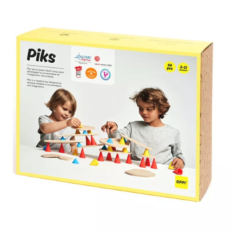 Two kids play with the Piks Construction Big Kit, building structures using colorful cones and platforms. The box shows the brand name, is recommended for ages 3-12, and contains 64 pieces. The children appear focused and engaged with this creativity-fostering toy.