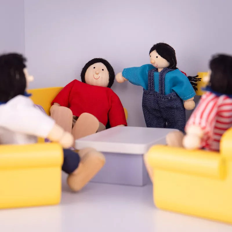 Four Multicultural Dolls – Asian Family sitting around a small table in a room with yellow chairs and a blue wall; one doll in a blue shirt gestures as if speaking to another in a red shirt