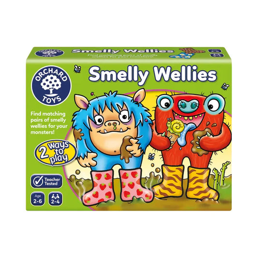 Box cover for Orchard Toys Smelly Wellies, showcasing two vibrant cartoon monsters in mismatched wellies against a green background. The text emphasizes "2 ways to play" and is suitable for ages 2-6, with a teacher-tested label.