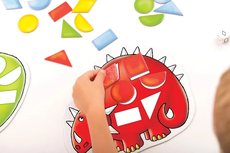 A child engaging with the Orchard Toys Dotty Dinosaurs set, placing vibrant geometric shapes on a red dinosaur-shaped board. Surrounding them are assorted shapes including circles, triangles, and rectangles, creating a playful educational scene focused on shape and color recognition.