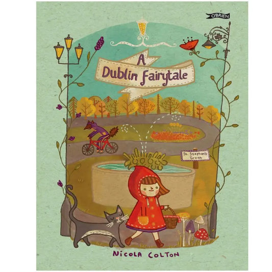 Book cover for "A Dublin Fairytale" shows a girl in a red hood carrying a basket, with a gray cat, cyclist, fountain, and autumn trees set in St. Stephen’s Green park.