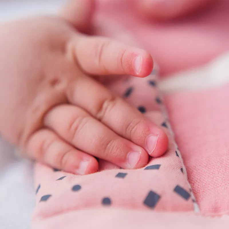 A close up of a person holding an Organic Activity Baby Toy Mouse.