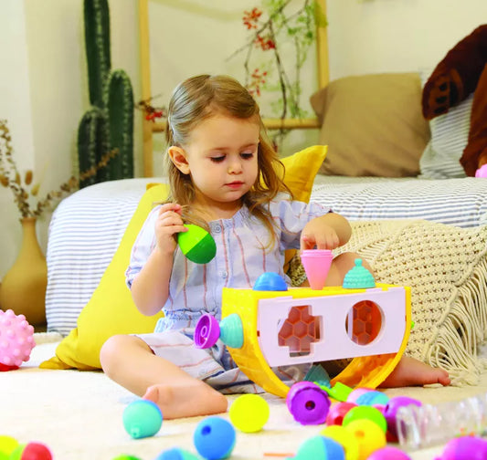 A little girl sitting on the floor playing with Lalaboom Shape Sorter-Balancing Game - 9 PCS.