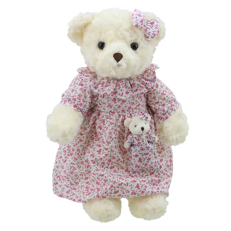 A Wilberry Dressed Animal Bedtime Bear Nightie wearing a floral dress with a matching bow on its head. The teddy is holding a smaller baby bear, also dressed in a matching floral outfit. Both bears are cream-colored and have a soft, fluffy appearance, making them the perfect birthday present.