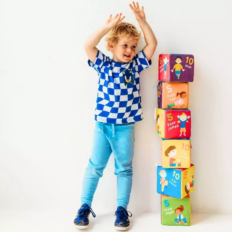 A young boy standing in front of a stack of CubeFun Exercise DUE 2024 blocks at a kids party game.