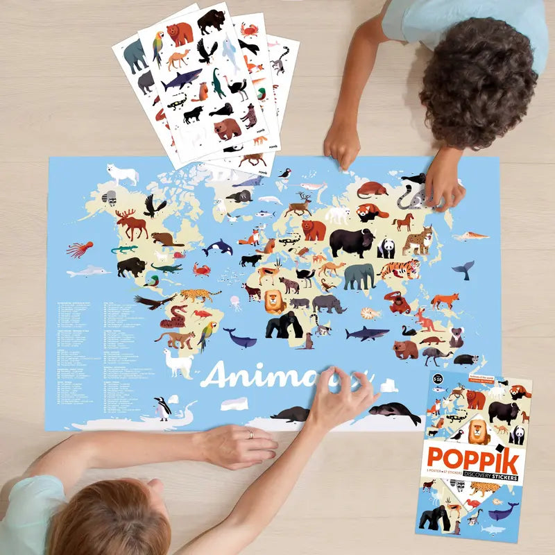 Two children are placing animal stickers on the Poppik Discovery Sticker Poster – Animals of the World, identifying creatures from each region. Animal sticker sheets and the Poppik box are on the table, making it a fun educational activity.