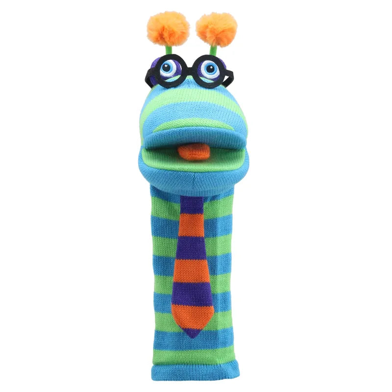 The Puppet Company Sockette Puppet Dylan is a colorful knitted puppet featuring vibrant blue and green stripes, adorned with black circular glasses topped with orange pom-poms. It has wide-open eyes, an orange felt mouth, and comes with a patterned tie. Additionally, this charming hand puppet includes a fun squeaker for added delight.