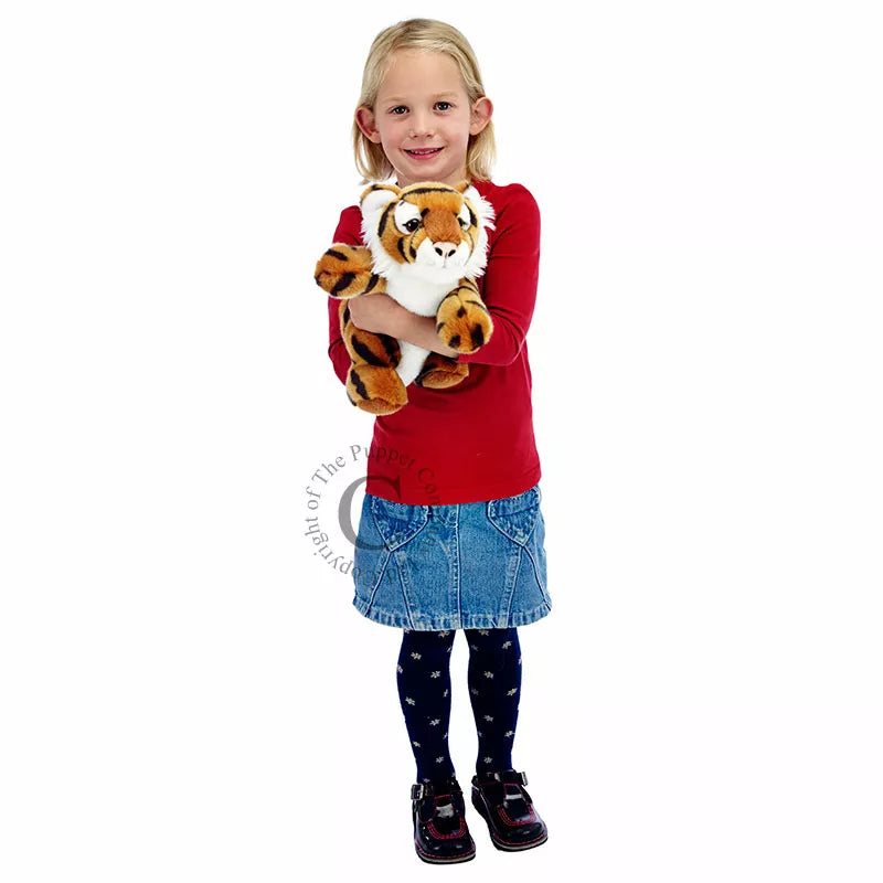 A little girl holding The Puppet Company Full-bodied Hand Puppet Tiger.