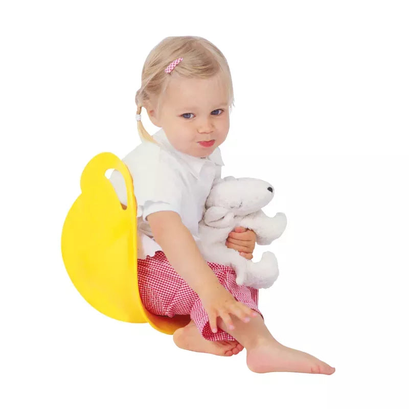 A young child with a pouty expression sitting on a yellow potty while holding a Spinner Blue.