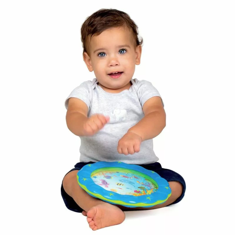 A baby sitting on the floor playing with the Halilit Wave Drum music toy.