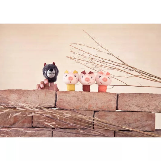 Four whimsical Lilliputiens Louis The Wolf And The 3 Little Pigs Finger Puppets perched on a rustic brick ledge, with delicate dried grasses adding a touch of nature's elegance in the background.