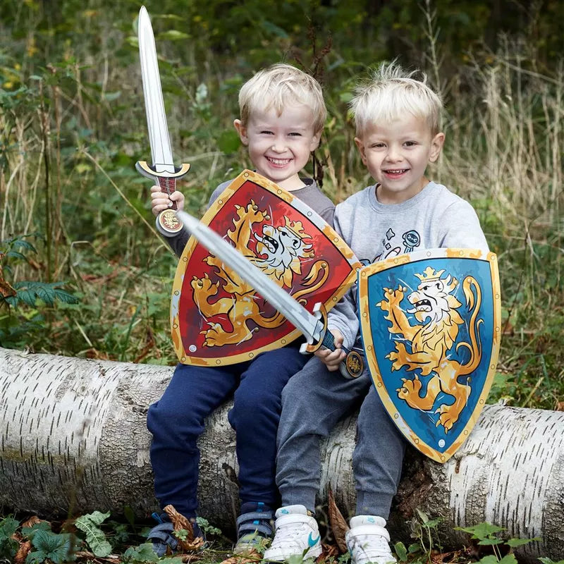 Two kids with Liontouch Noble Knight Set for 2 pretending to have a puppet show while sitting on a log in the woods.