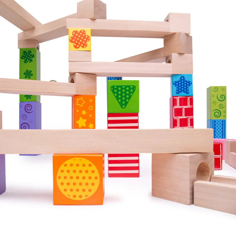 The Bigjigs Marble Run features colorful wooden blocks and shapes like circles, stars, and stripes in bright orange, green, blue, and red. It's an educational toy that encourages creativity by allowing kids to stack blocks into playful configurations for imaginative play.