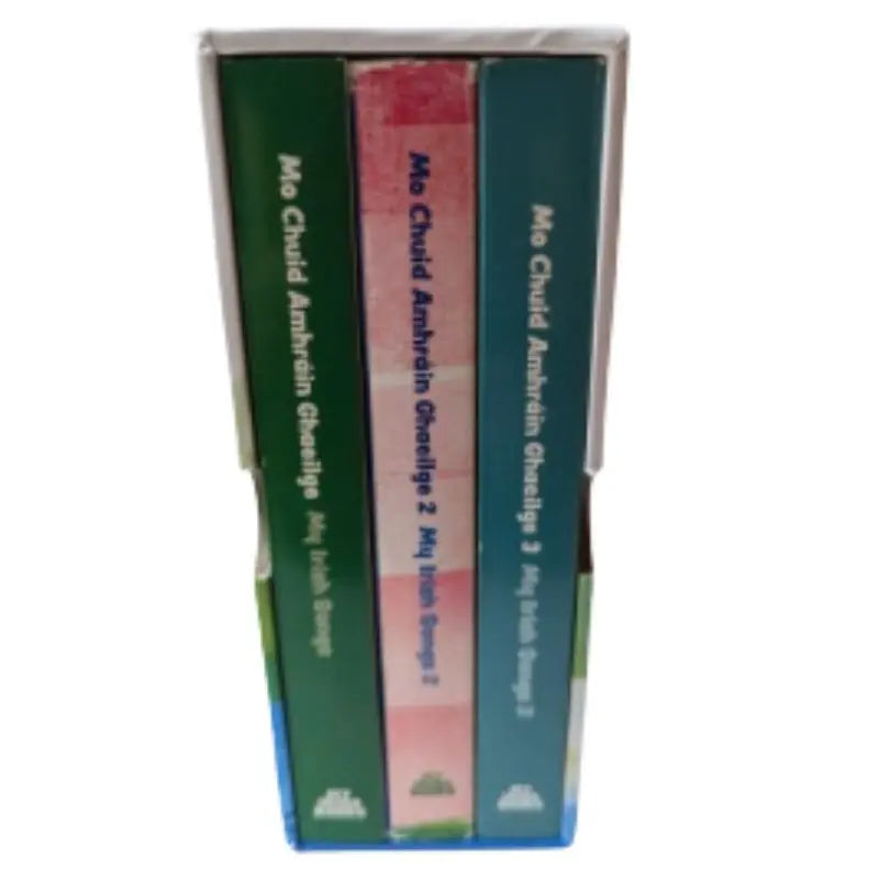 The "Bailiúchán Mo Chuid Amhráin Ghaeilge" box set includes three Irish children's song books (volumes 1–3) from the My Irish Books series, featuring green and red spines with titles and authors in white and blue text.