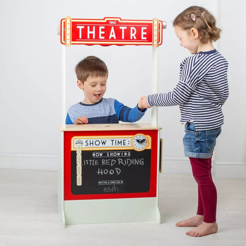 A young boy and girl play with the Tidlo Playshop and Puppet Theatre with FREE Finger Puppets. The boy, behind the stand labeled "THEATRE" and "NOW SHOWING LITTLE RED RIDING HOOD," hands something to the girl.