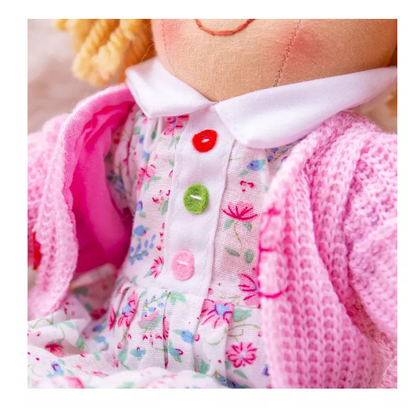 A close up of a Bigjigs Poppy Doll Small wearing a pink sweater.