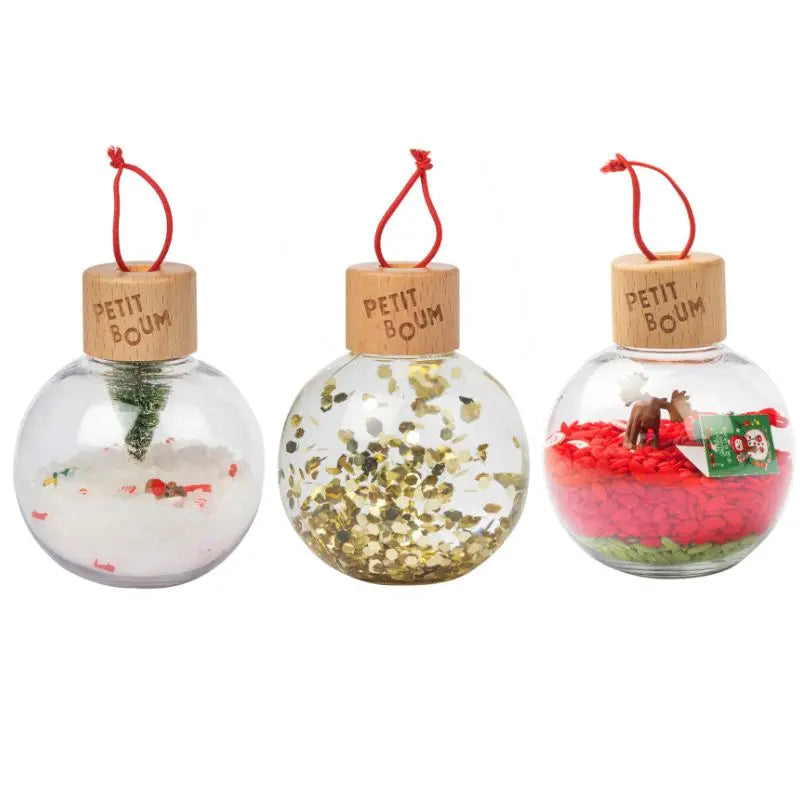 Christmas Sensory Baubles: set of three clear, unbreakable round ornaments with wooden caps and red loops. Each bauble contains festive decor—a snowy tree, gold sequins, or miniature Christmas figures on colorful bases.