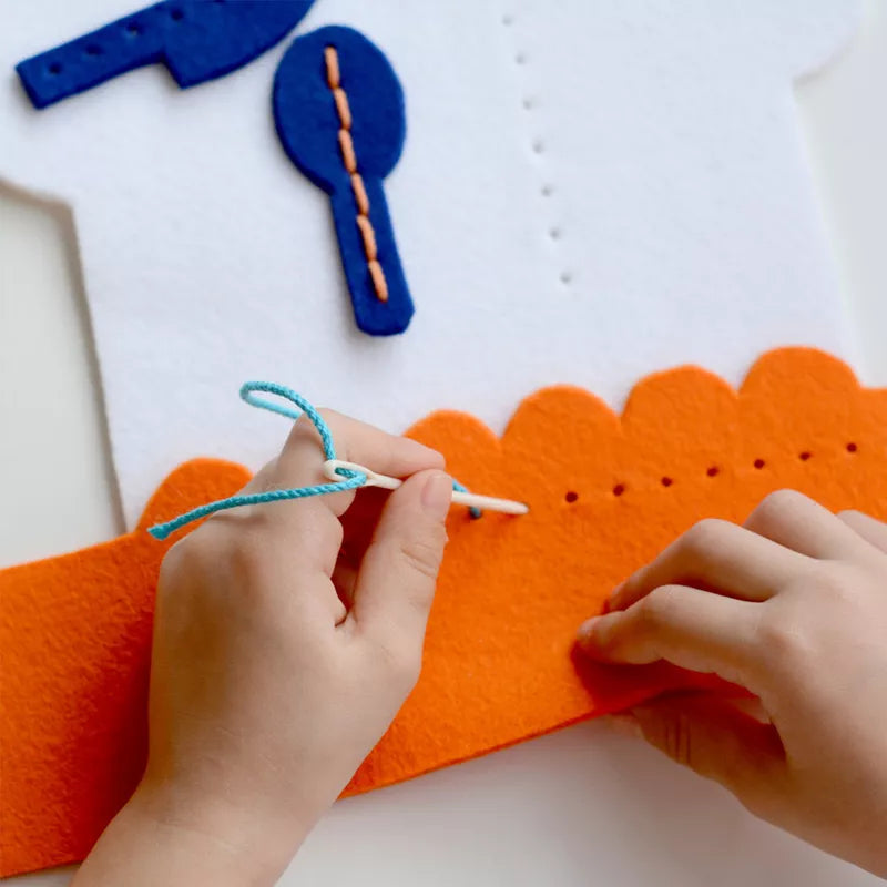 A child is making a Cook Chef Sewing Kit house with scissors.