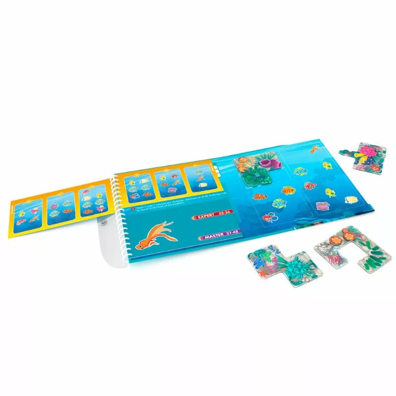 The Smartgames Coral Reef is a vibrant open puzzle book featuring sea-themed pieces. Various fish and ocean graphics glide over a blue background. Loose pieces beside the book suggest it's ideal for educational fun at home or as a magnetic travel game for kids who love puzzles.