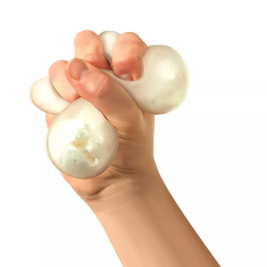 A human hand squeezing two Snow Ball Crunch Needoh toys, with visible deformation due to the pressure, against a white background.