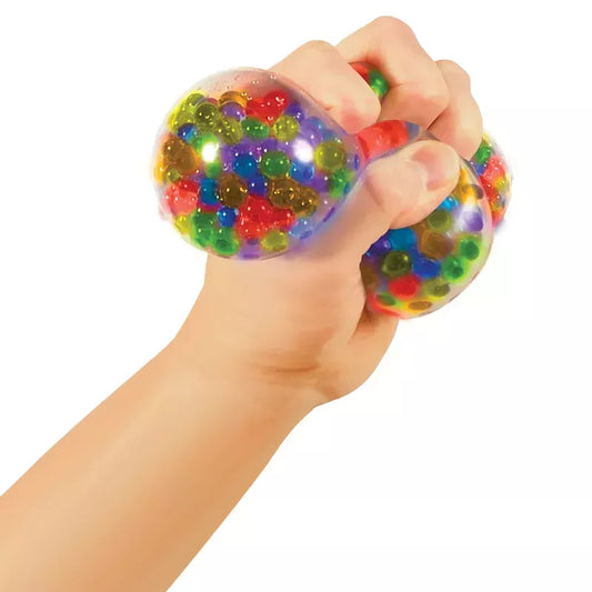 A hand squeezing a transparent Squeezy Peezy NeeDoh filled with colorful beads.