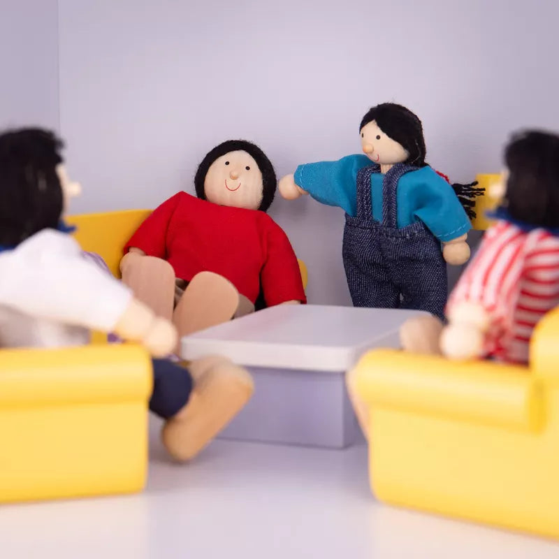 Four Multicultural Dolls – Asian Family sitting around a small table in a room with yellow chairs and a blue wall; one doll in a blue shirt gestures as if speaking to another in a red shirt