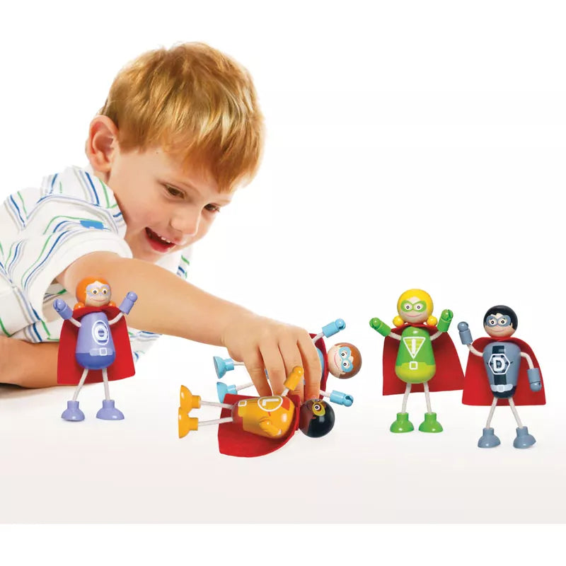 A young boy with red hair joyfully engaging in imaginative play with the Superhero Figure Pack and dollhouses on a white background.