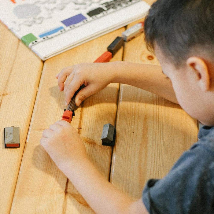 A young boy is playing with puppet-themed TOOBS® Figurines on a wooden table.