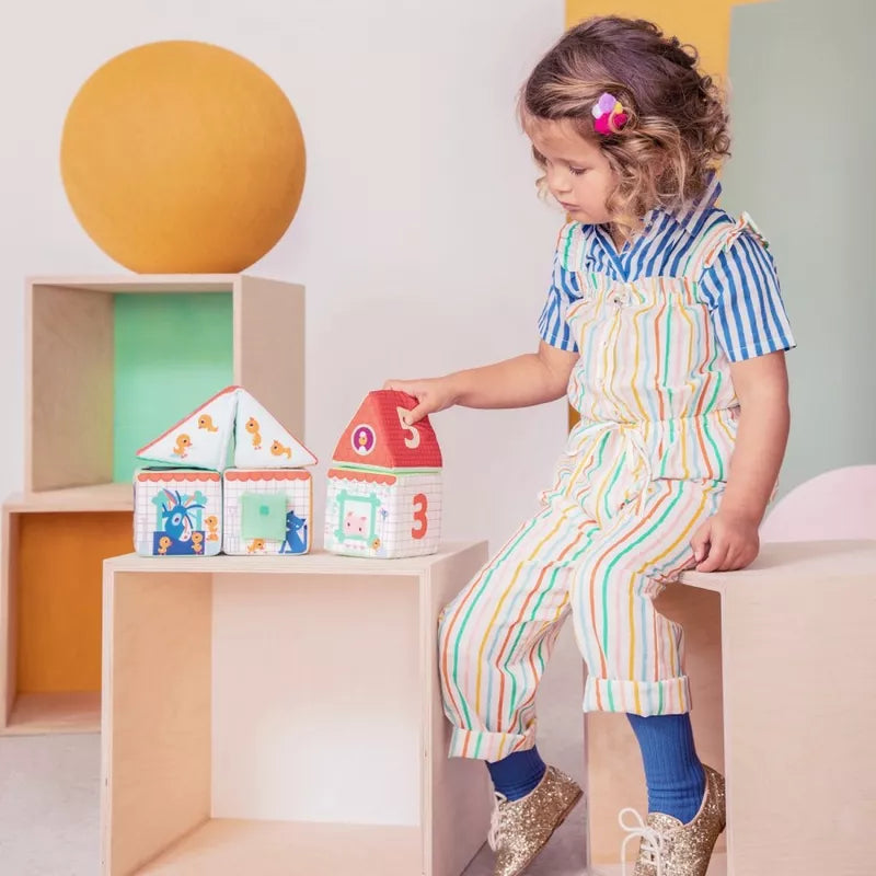 A little girl playing with Lilliputiens Farm House Stacking Cubes.