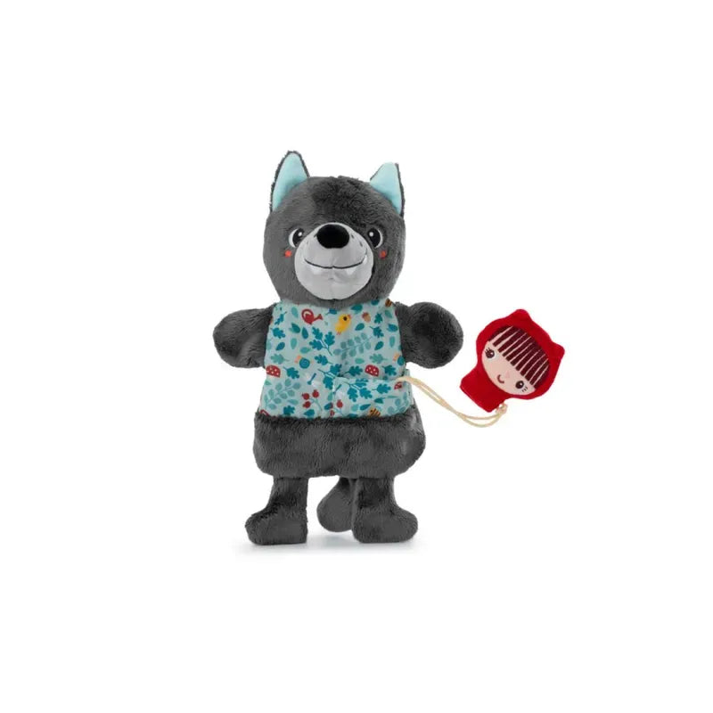 A Lilliputiens Louis Wolf Handpuppet wearing a blue floral-patterned shirt and holding a Little Red Riding Hood Finger Puppet attached by a string. The wolf has a friendly expression and stands on two legs. Perfect for imaginative and creative play, the background is plain white.