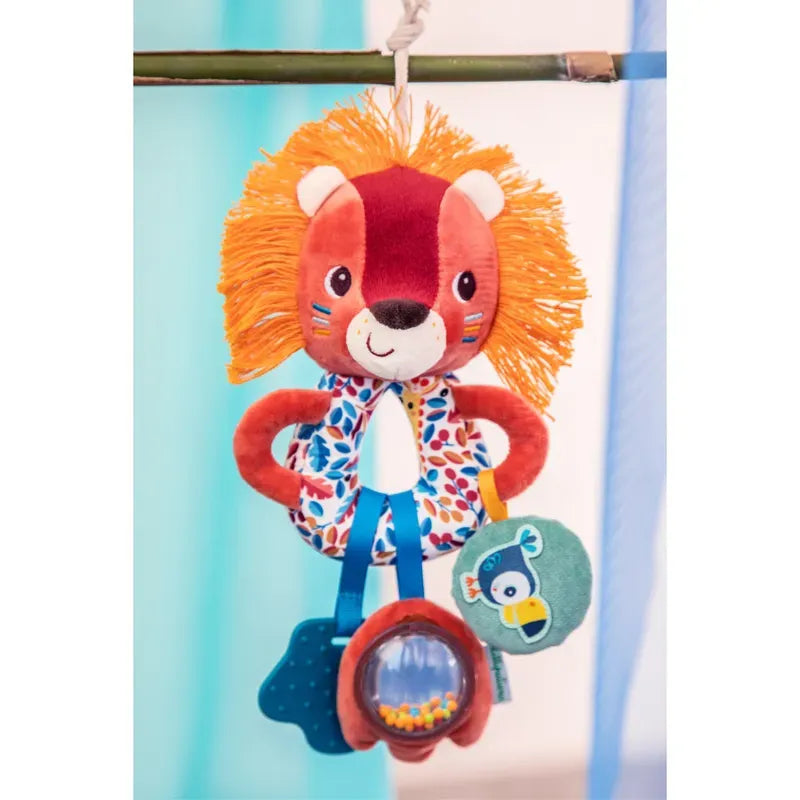 A Lilliputiens Jack Multi Activity Rings with a vibrant orange mane and multicolored ears. The lion has a friendly face and wears a patterned vest. Hanging from its body are three small soft toys, including a blue star, a green bird, and a clear circle with beads—a perfect baby’s rattle for cognitive development.