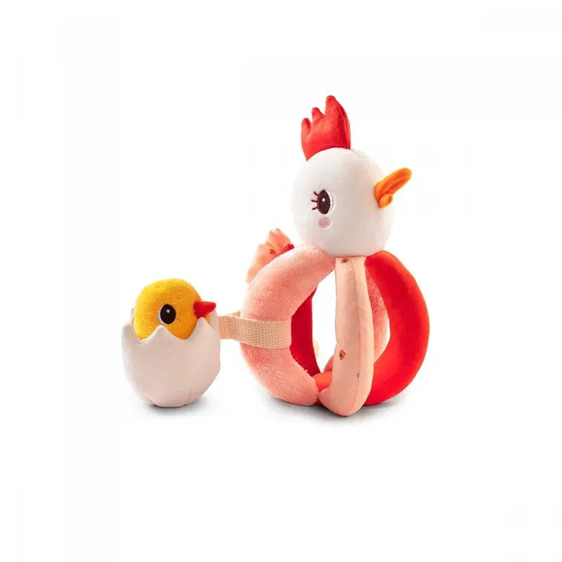 A Lilliputiens Paulette Rattle With Handles featuring a white hen with a red comb and orange beak, designed as a sensory toy. The yellow chick, emerging from a white eggshell, doubles as a baby rattle and is connected to the hen with a strap. Both pieces are machine-washable for easy cleaning.