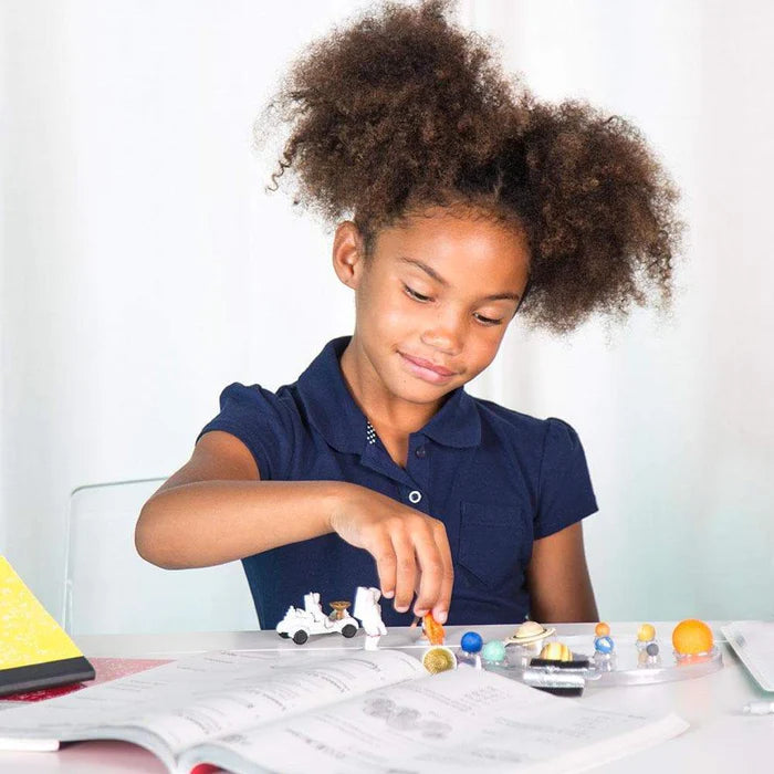 A young girl is playing with a Space set at a desk.